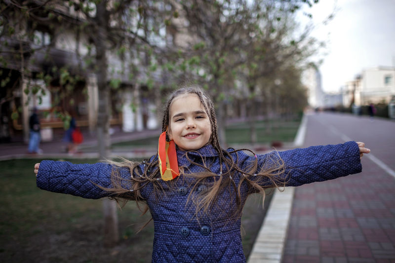 Portrait of smiling girl standing against tree