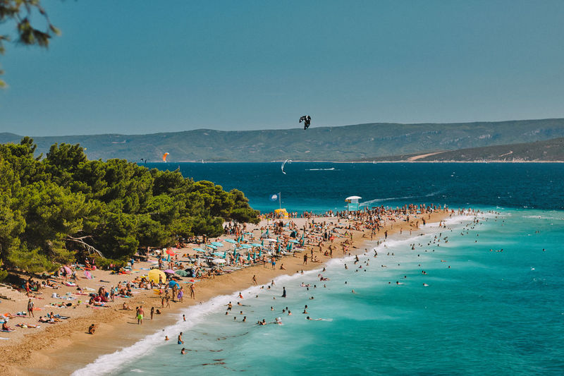 People on beach against clear blue sky