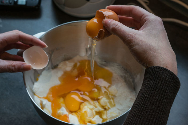 Cropped hand putting egg in flour and butter
