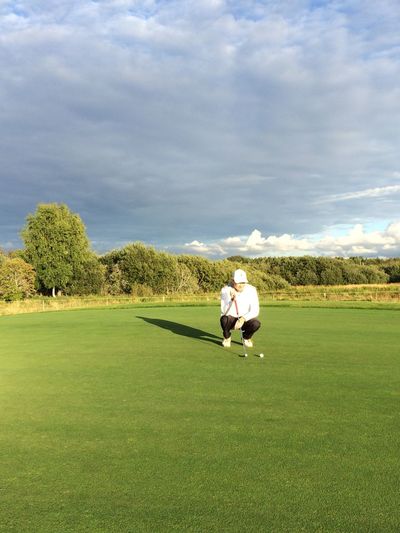 Man crouching on field at golf course