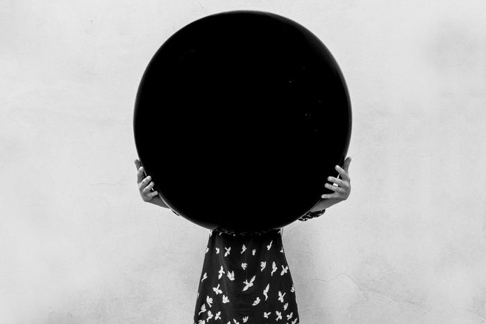 Girl standing behind circle shaped balloon against white background