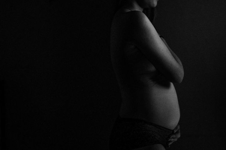 Midsection of woman standing against black background