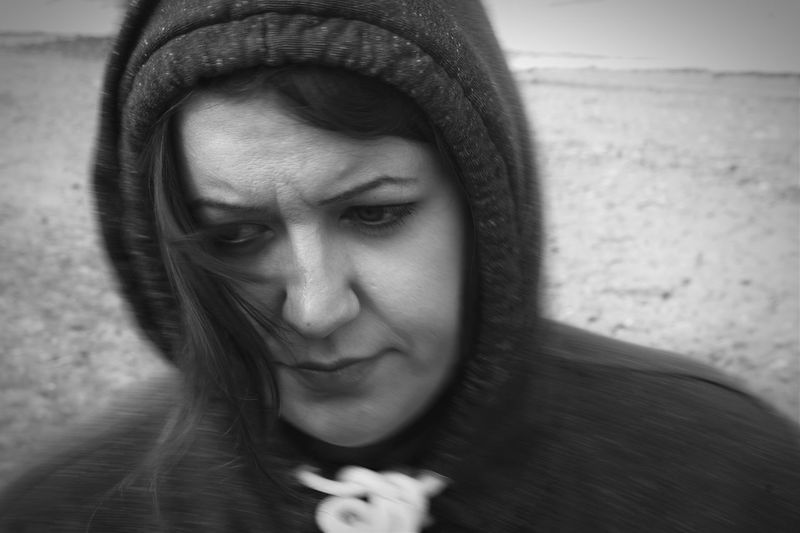 Close-up of thoughtful woman in hooded shirt at beach