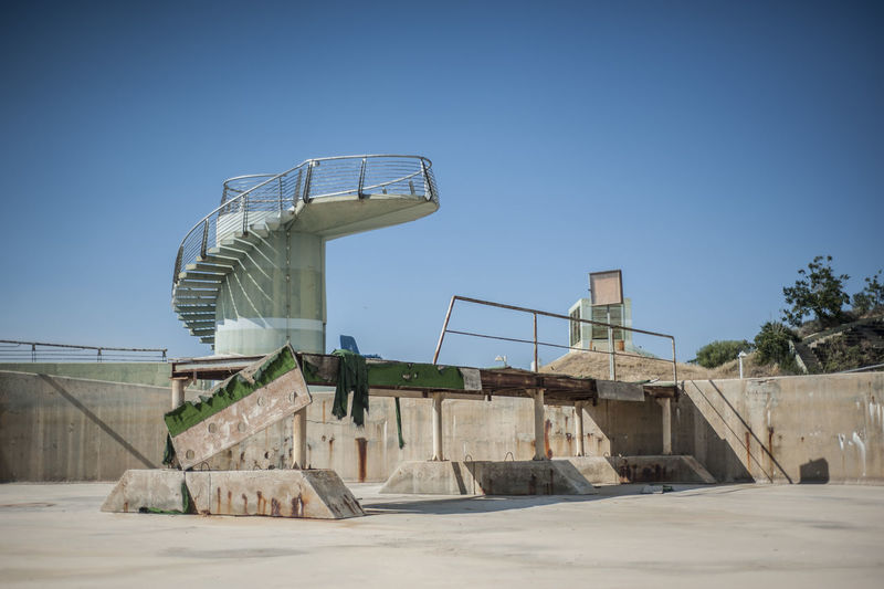 Steps in abandoned stadium against clear blue sky
