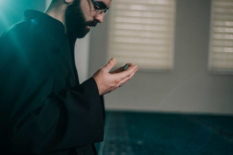 Side view of young man praying in mosque