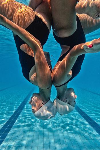 Side view of female swimmers synchronized swimming in pool