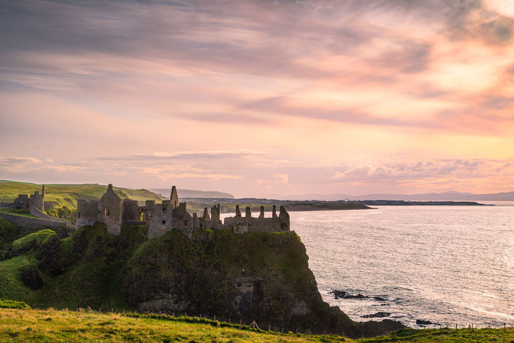 Dramatic sky over ruins of dunluce castle perched on the edge of cliff, northern ireland