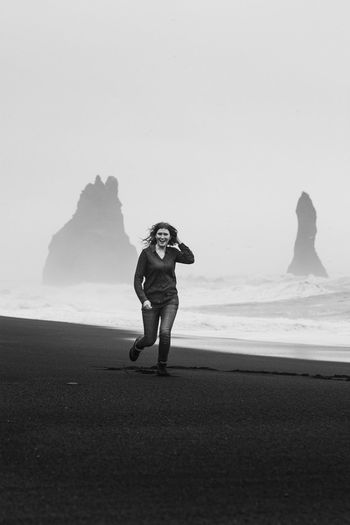 Excited lady running along iceland beach monochrome scenic photography