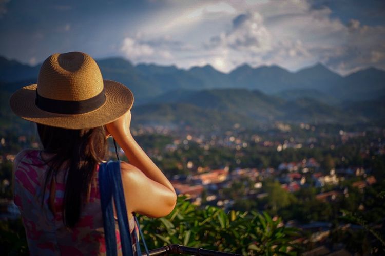 Woman in hat looking at mountains against sky
