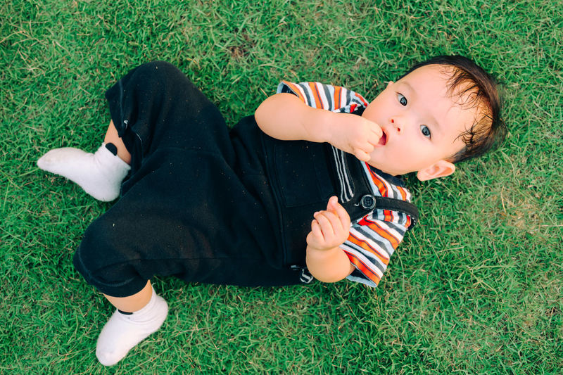 High angle view of boy lying on grassy field
