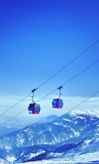 Overhead cable car over snowcapped mountains against blue sky