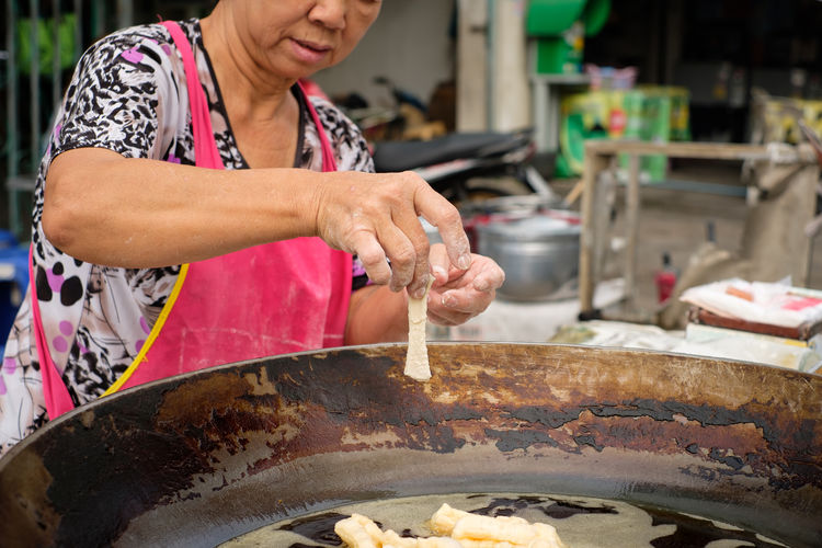 Senior woman wearing apron preparing food at market stall