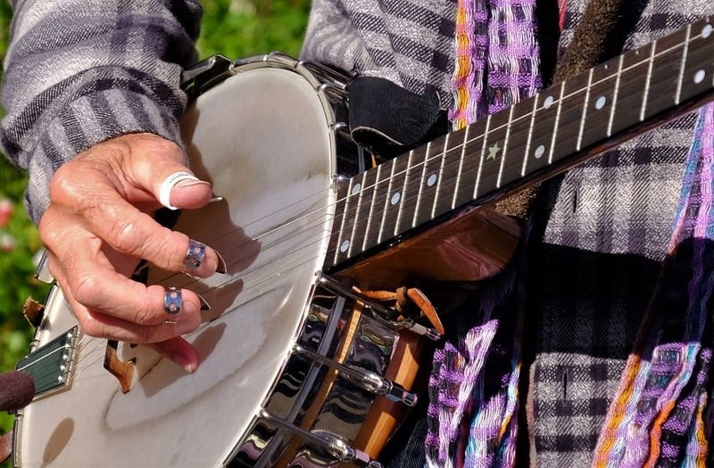 Midsection of man playing banjo with fingerpicks