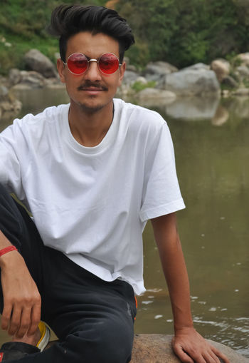 Young man wearing sunglasses sitting in lake