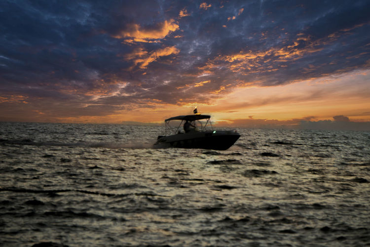 Boat on sea against sky during sunset