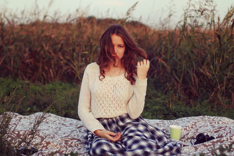 Portrait of beautiful young woman sitting on blanket over grass
