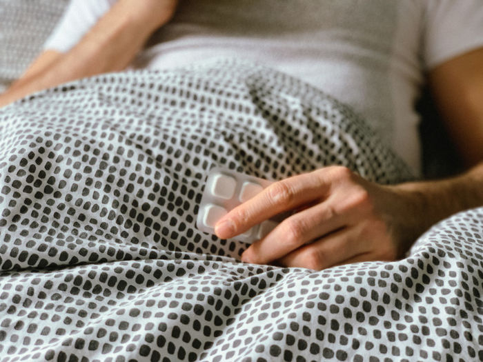 Middle aged man is sick at home, having flu or hangover. middle aged man is in bed having flu covid