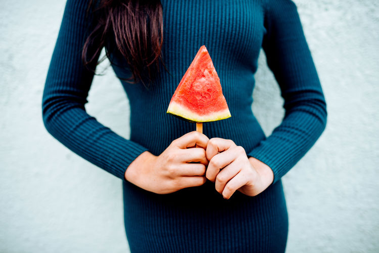 Woman holding watermelon slice on a stick