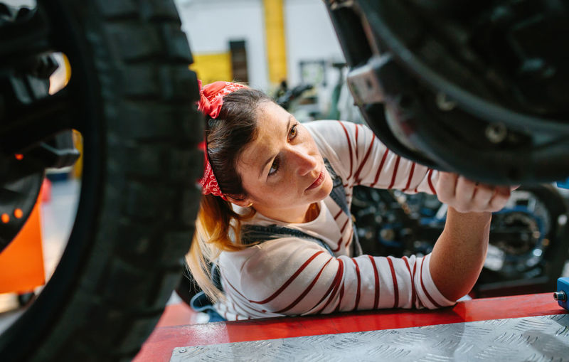 Mechanic woman checking motorcycle on factory