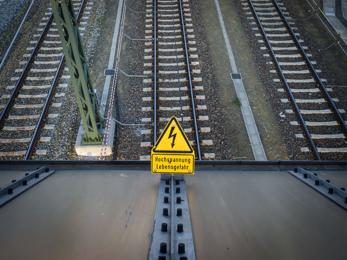 High angle view of high voltage danger sign on railroad tracks