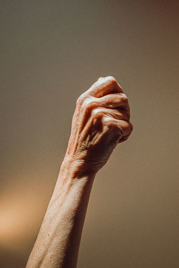 Cropped hand of woman clenching fist against wall