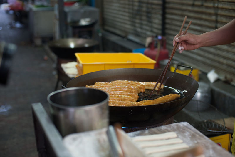 Cropped hand of woman frying food in wok at market