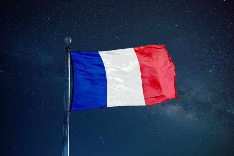 Low angle view of french flag against star field sky