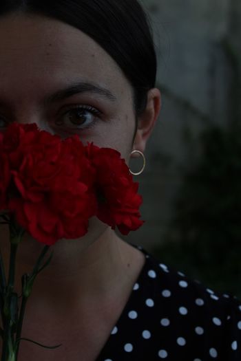 Close-up portrait of young woman with red flower