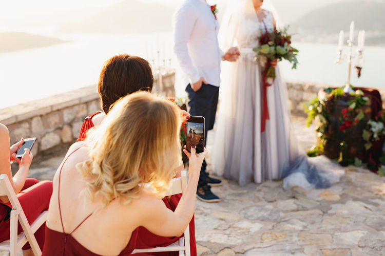 Rear view of woman photographing during ceremony