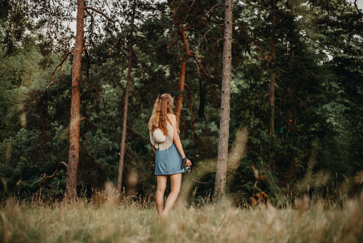 FULL LENGTH OF WOMAN STANDING BY TREES IN FOREST