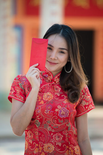 Young woman holding red while standing outdoors