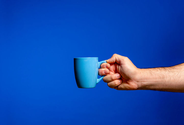 Midsection of man holding drink against blue background