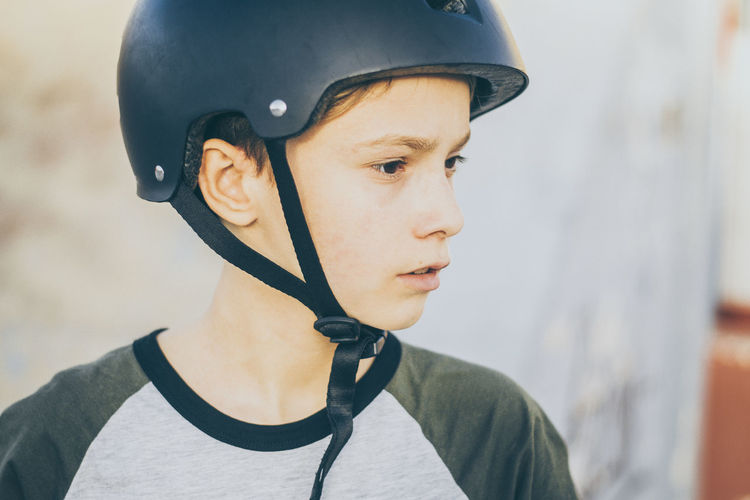 Portrait of trendy young skater at the skatepark with helmet looking away teenager enjoying outdoor