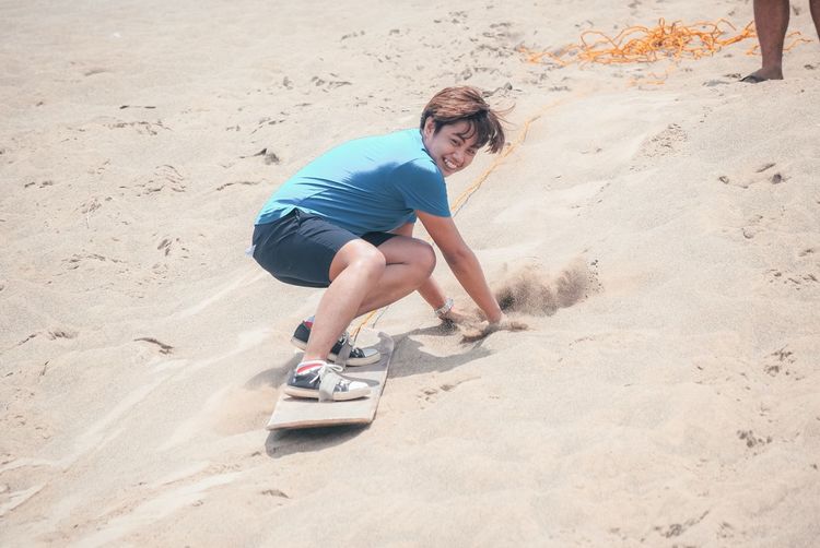 Full length portrait of smiling young man on beach