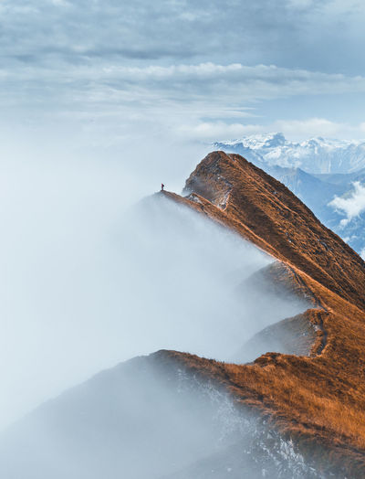 Distant view of man standing on mountain ridge