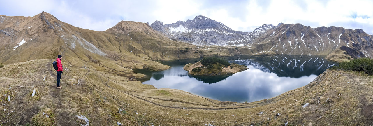 Full length of woman looking at lake against mountain range