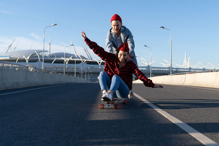 Carefree hipsters couple skateboarding together. trendy man and woman enjoy time riding longboard