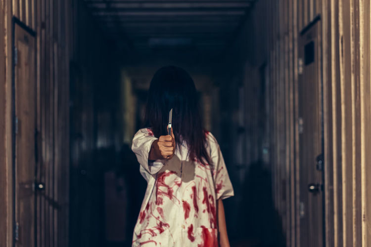 Woman wearing blood stained cloth while holding knife