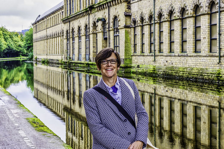 Portrait of smiling woman standing against building