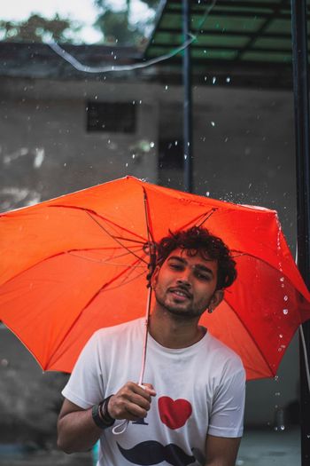 Man holding umbrella standing during rainy season