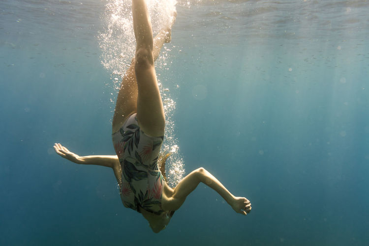 Woman swimming upside down in sea