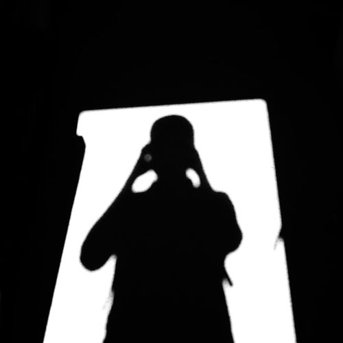 Silhouette of woman standing against wall