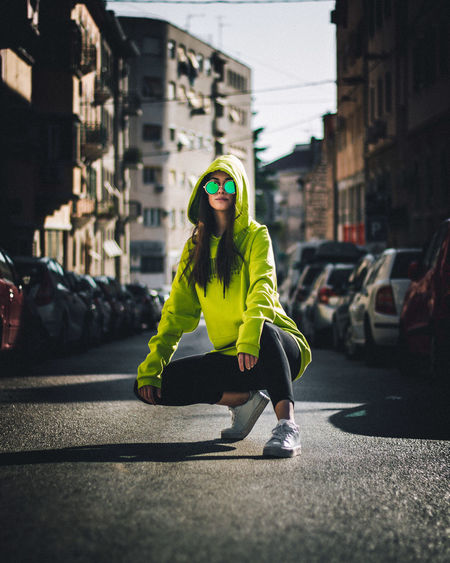 Portrait of woman crouching on city street