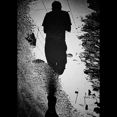 Rear view of silhouette man standing by puddle