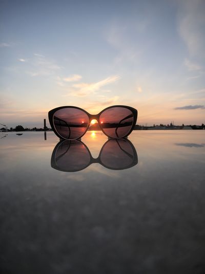 Sunglasses on beach against sky during sunset