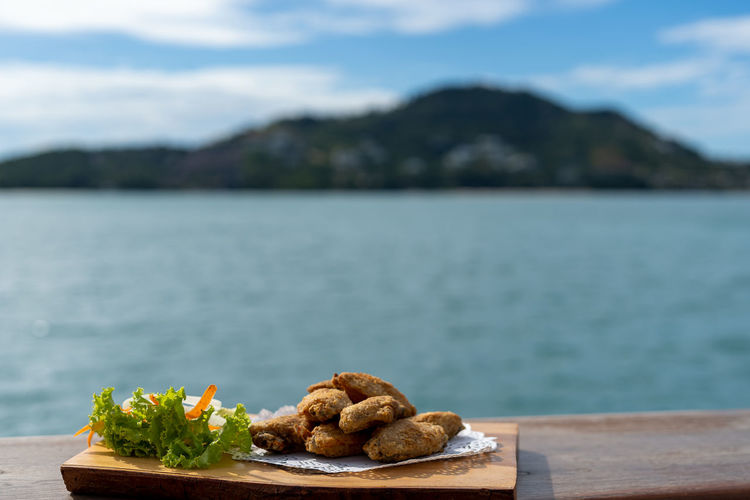 Close-up of food on table by sea against sky