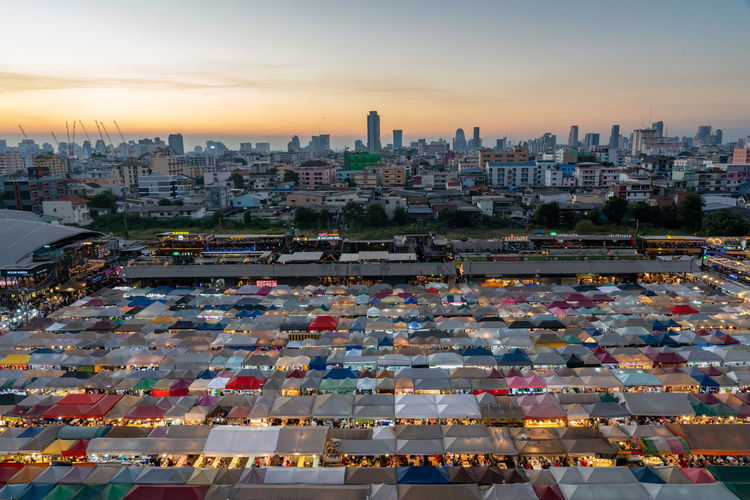 High angle view of city buildings and bangkok train night market  during sunset