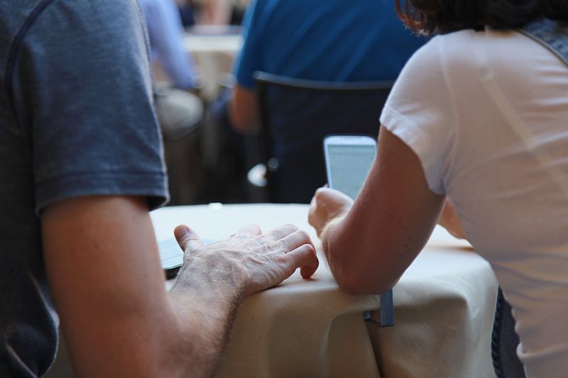 Midsection of people using mobile phone on table