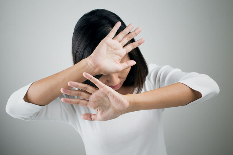 Woman showing stop gesture while standing against white background