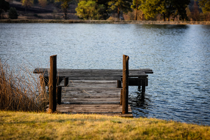 Empty bench on pier by lake